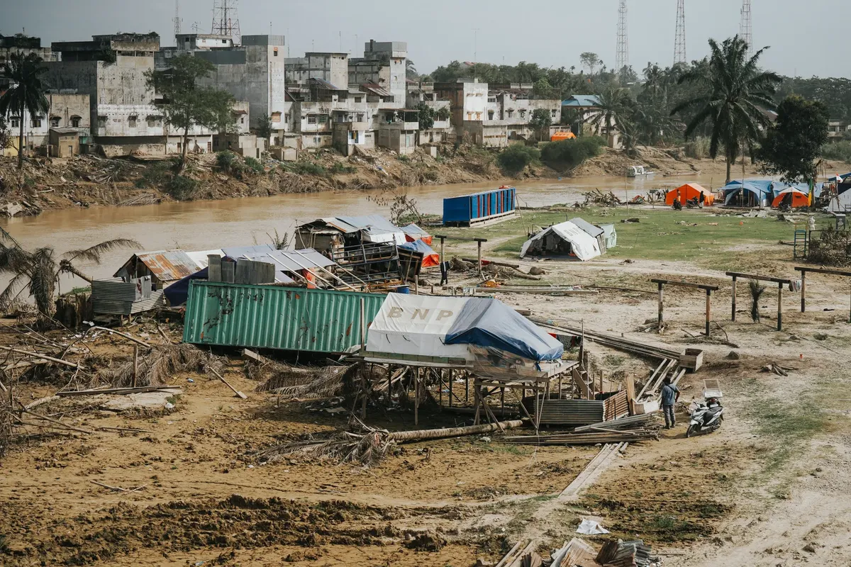 Flood aftermath in Aceh, Indonesia with temporary shelters and debris.