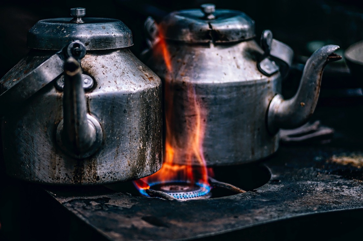 A rugged backpack and a portable camping stove on a rocky terrain.