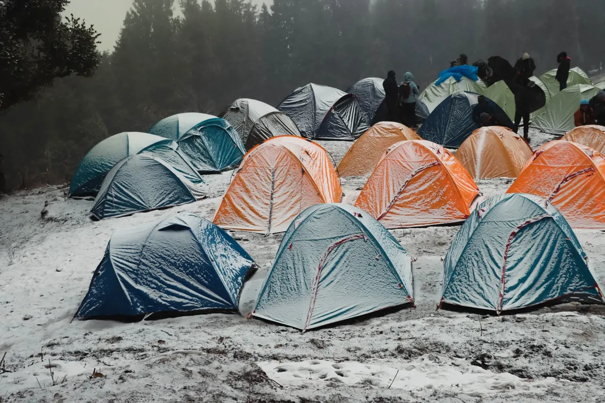 A vibrant campsite with colorful tents in a snowy forest in Singtur Range, India, capturing the essence of winter camping.