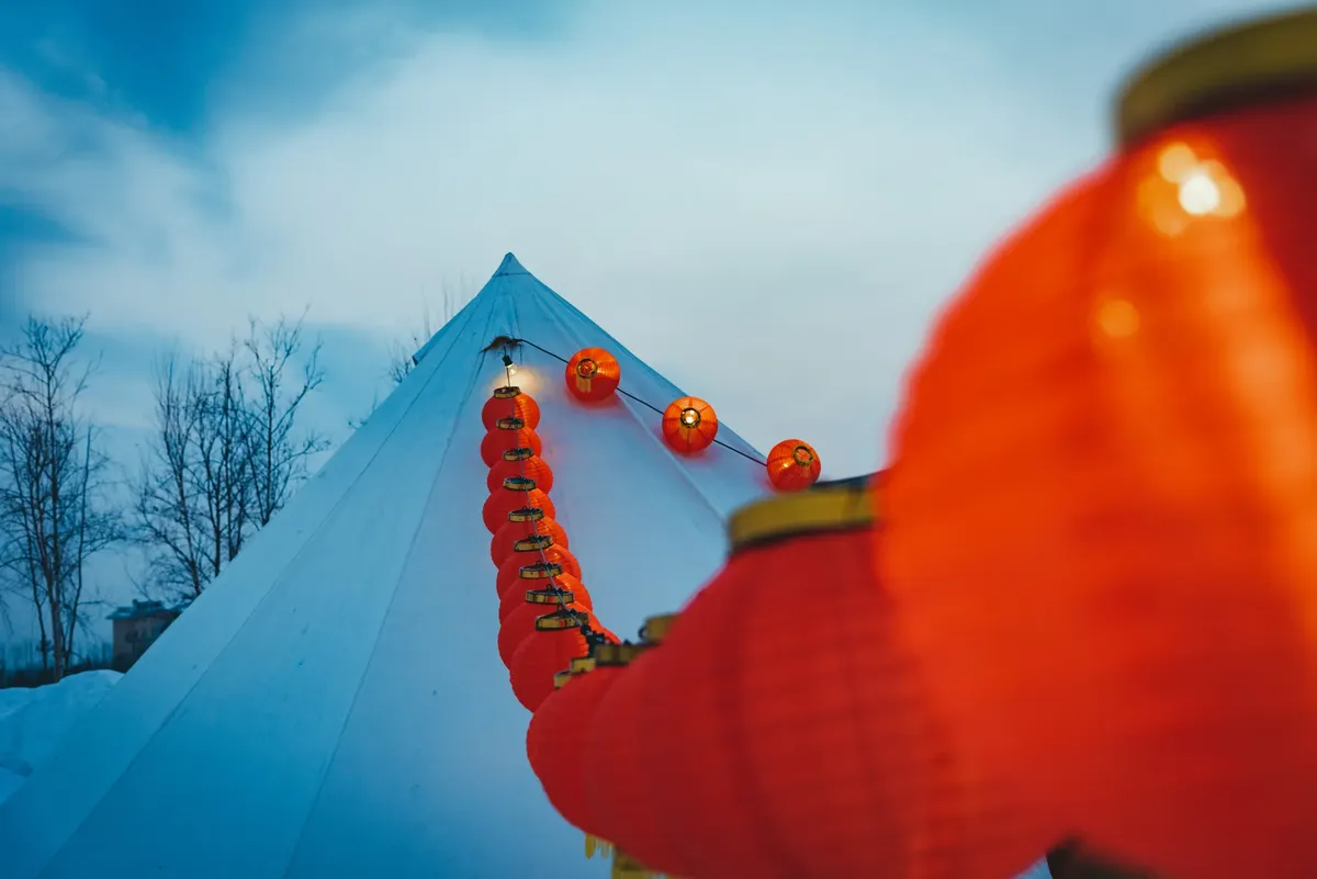 Vibrant red lanterns adorning a snowy tent, symbolizing festive winter celebration.