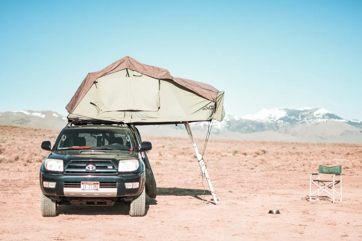 Outdoor adventure in Oreana Desert featuring SUV with rooftop tent and scenic mountains.